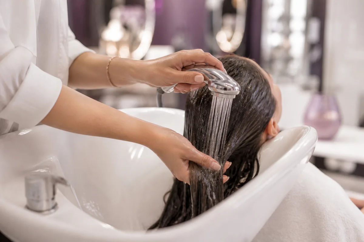 Rinçage des longueurs à l&rsquo;eau tiède après le shampoing
